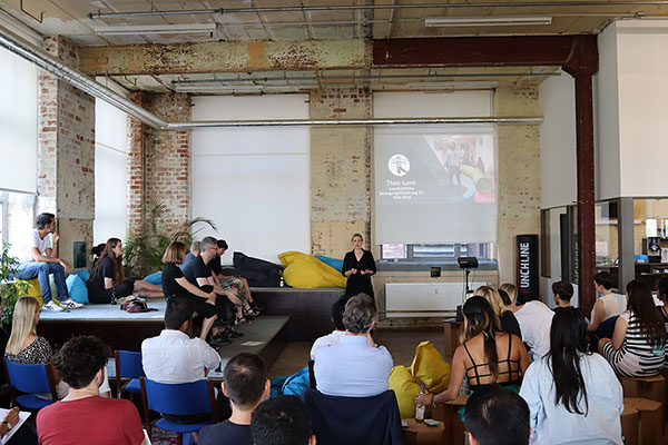 A women standing in front of an audience and pitching