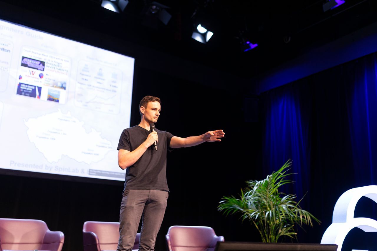 A photo of a men (investor) on the stage with a microphone pitching 
