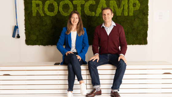 A photo of the two founders of Aquanzo. In the back you can see the RootCamp Logo on a green moss wall