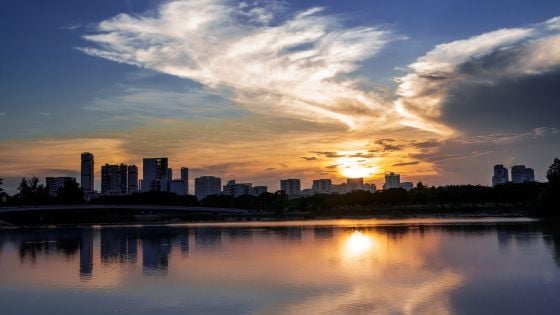 A photo of a lake with the sun is shining in the background