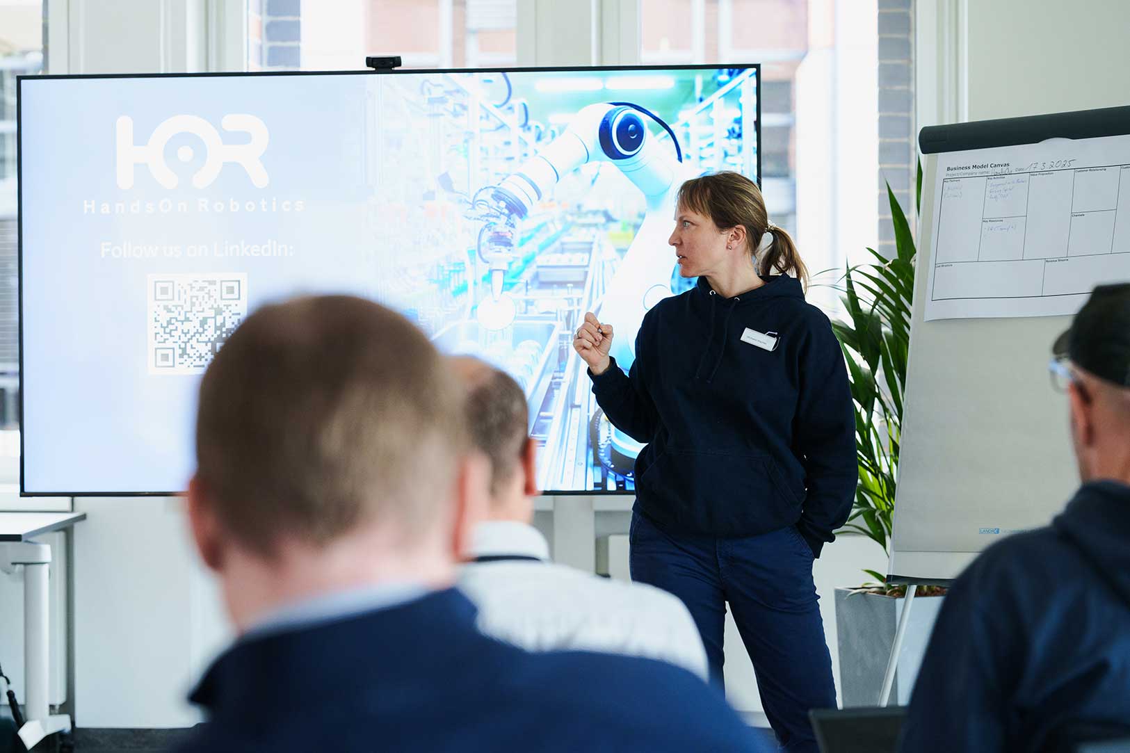 a picture of a women wearing a blue hoodie and presenting a slide on a tv screen
